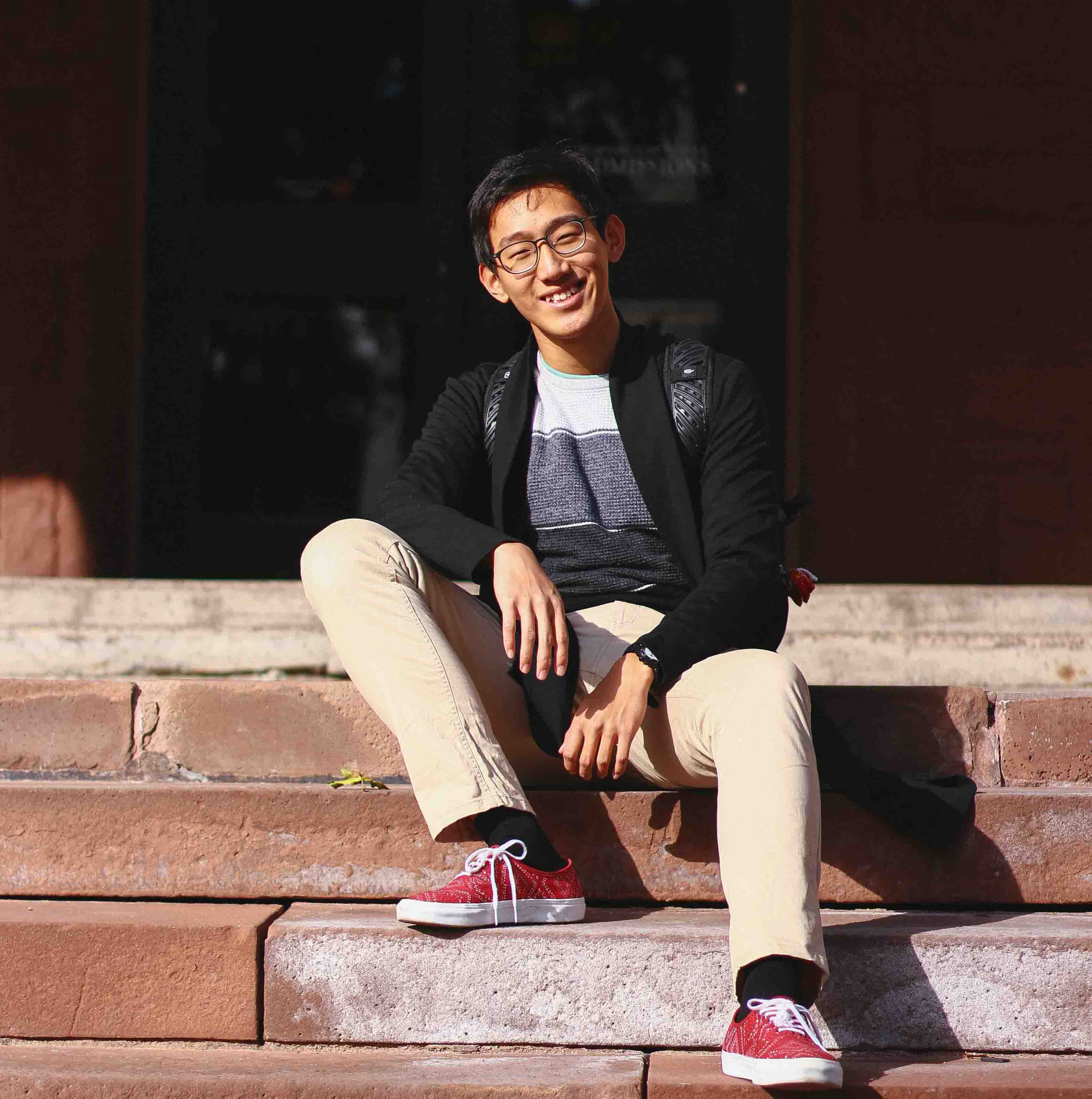 A picture of Chunyue Ma sitting on the stairs in front of a Wesleyan building.